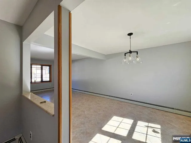 a view of empty room with window and chandelier