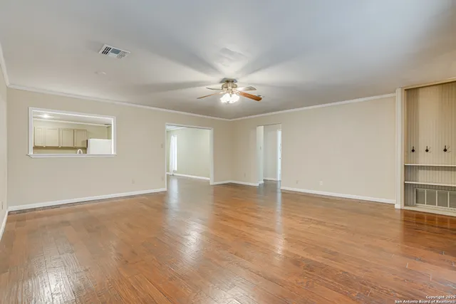 a view of an empty room with wooden floor and a window