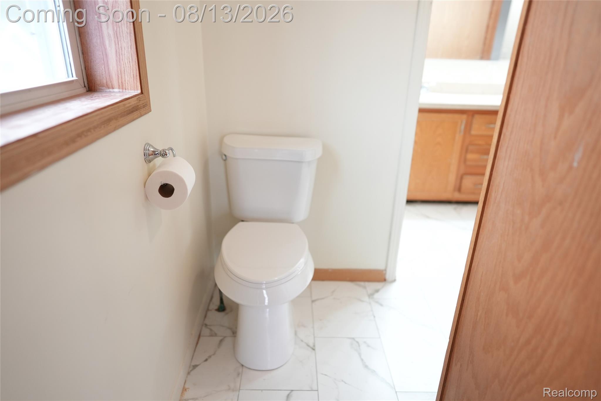 2018 John R Road Troy, MI 48083 - Photo 37 of 57 White toilet with a round bowl, natural wood-finish window trim, and white-veined floor tiling