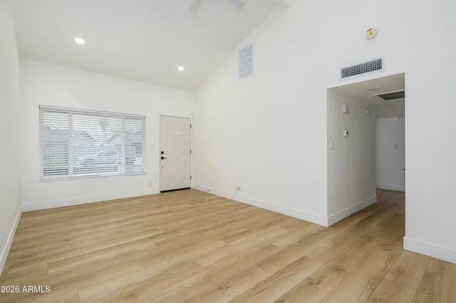 a view of an empty room with wooden floor and a window