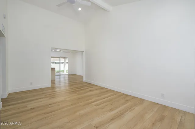 a view of empty room with wooden floor and fan