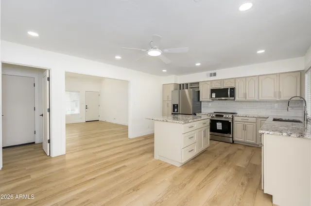 a large kitchen with stainless steel appliances granite countertop a stove a sink dishwasher and a refrigerator with wooden floor