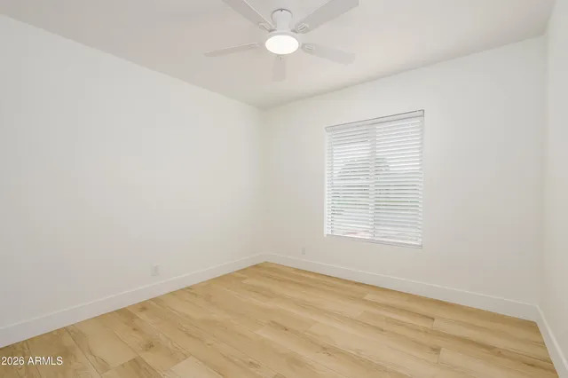an empty room with a window and ceiling fan