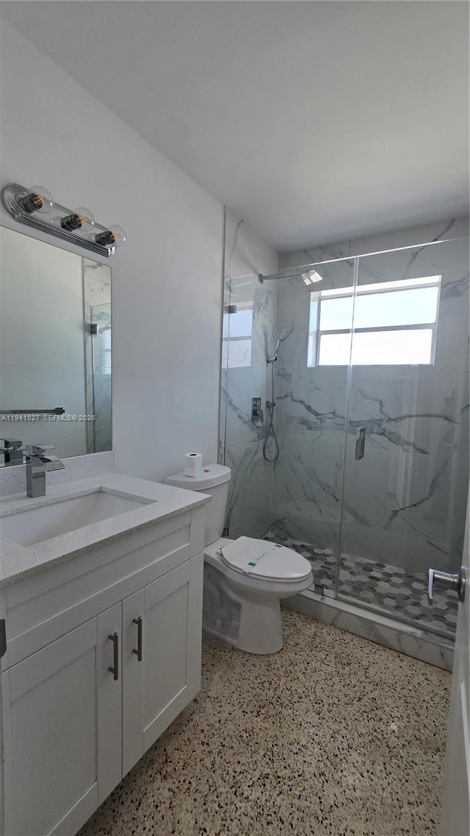 3312 Southwest 24th Terrace Miami, FL 33145 - Photo 7 of 13 a bathroom with a granite countertop toilet a sink a mirror and a shower