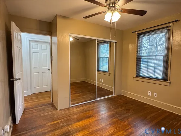 an empty room with wooden floor fan and windows