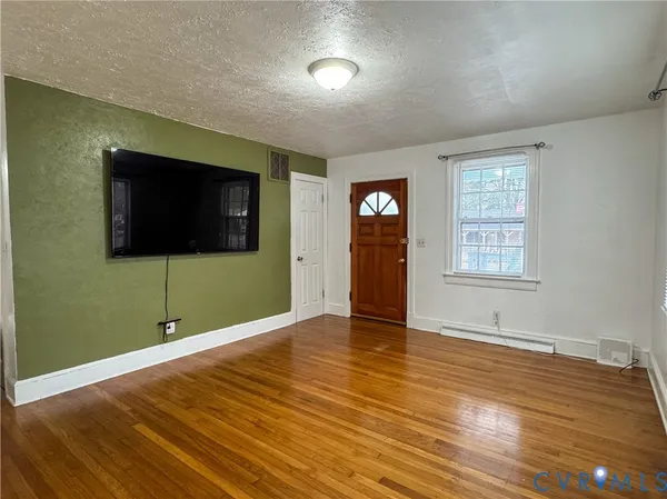 a view of an empty room with wooden floor and a window