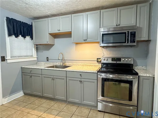 a kitchen with granite countertop a stove sink and cabinets
