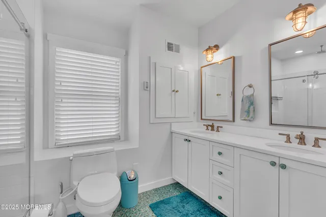 a bathroom with a double vanity sink toilet and a mirror