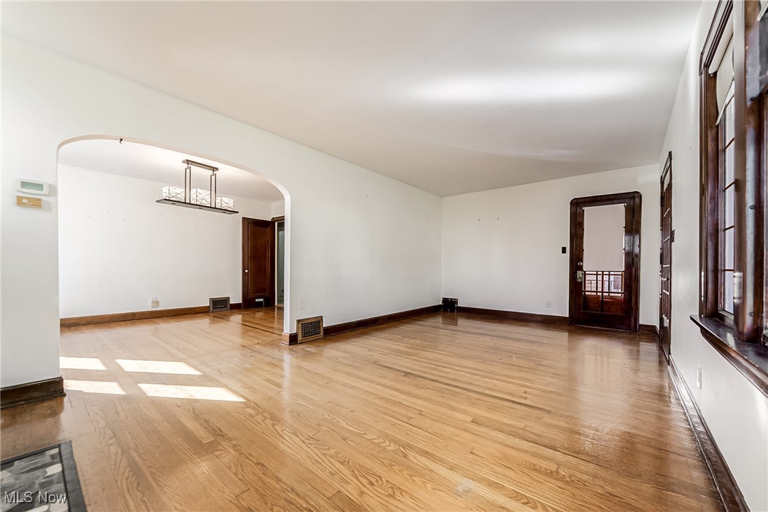 6711 Forest Avenue Parma, OH 44129 - Photo 8 of 33 Unfurnished room with light wood-style floors, arched walkways, and a chandelier