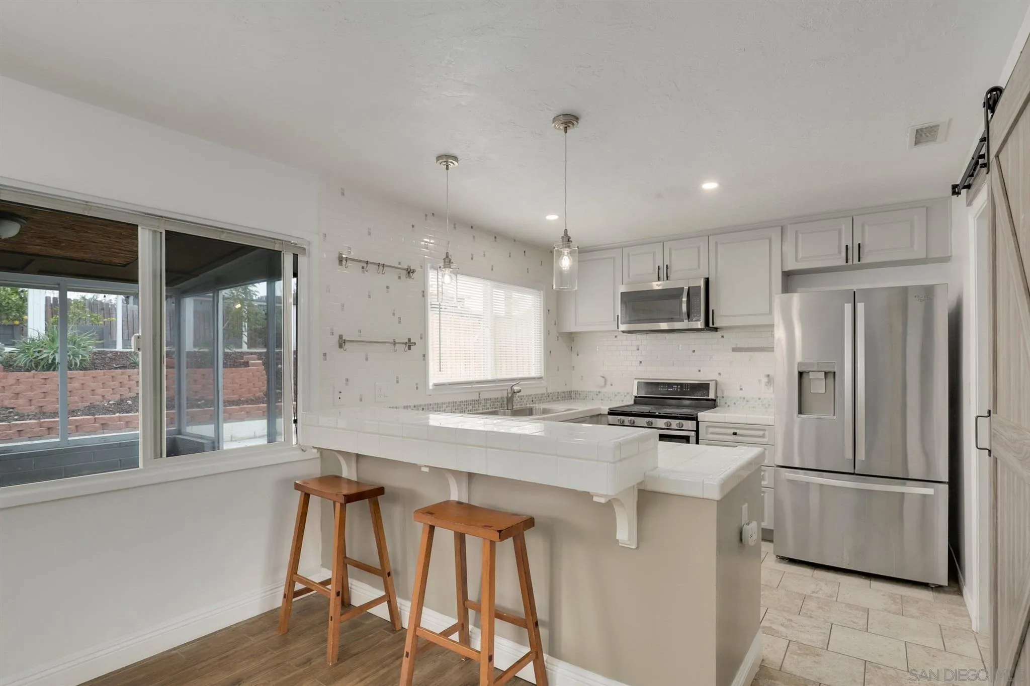 9753 Settle Road Santee, CA 92071 - Photo 3 of 31 a kitchen with stainless steel appliances granite countertop a refrigerator a stove a sink dishwasher a oven with white cabinets and wooden floor