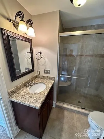 a bathroom with a granite countertop sink a toilet and shower
