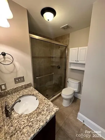 a bathroom with a granite countertop sink a toilet and shower