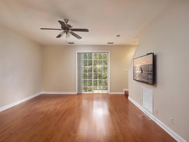 a view of an empty room with wooden floor and a window