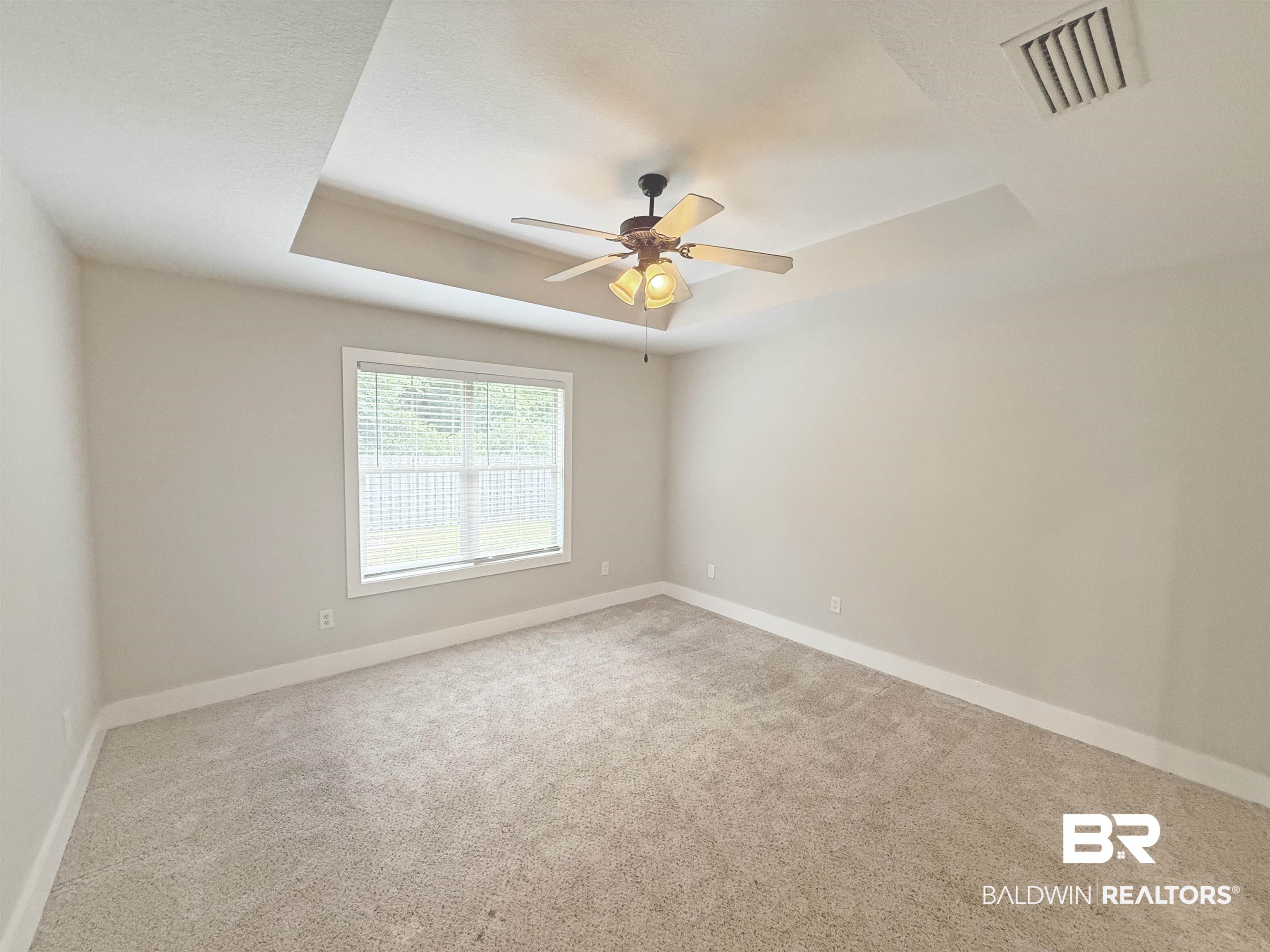 22023 Garland Loop Silverhill, AL 36576 - Photo 15 of 33 Carpeted spare room featuring a ceiling fan and a tray ceiling