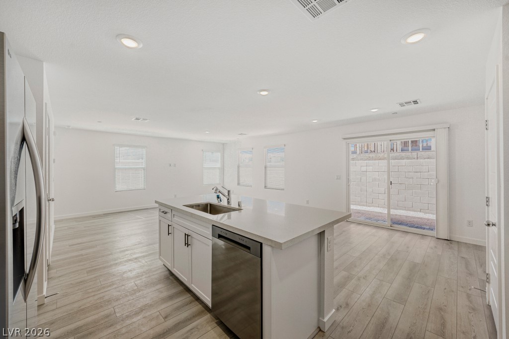 773 Fallen Phoenix Street Henderson, NV 89011 - Photo 11 of 28 Kitchen featuring white cabinetry, stainless steel appliances, a center island with sink, light wood-style flooring, and recessed lighting