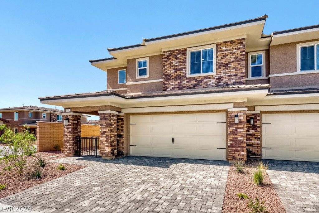 773 Fallen Phoenix Street Henderson, NV 89011 - Photo 2 of 28 Prairie-style house with stucco siding, decorative driveway, brick siding, an attached garage, and a gate