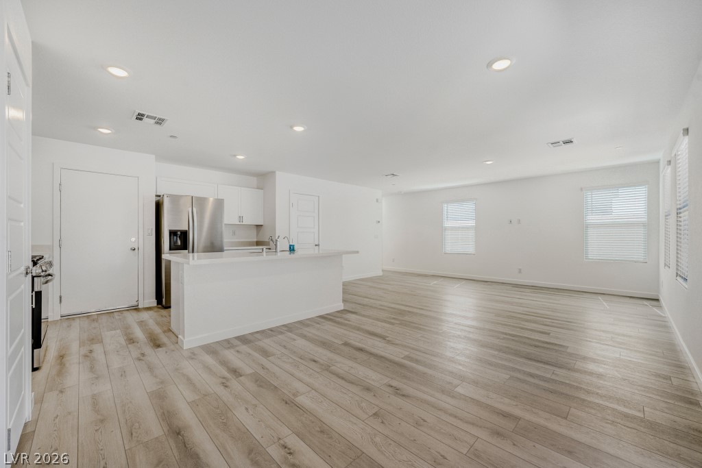 773 Fallen Phoenix Street Henderson, NV 89011 - Photo 28 of 28 Kitchen with a kitchen island with sink, white cabinets, open floor plan, stainless steel appliances, and light wood finished floors