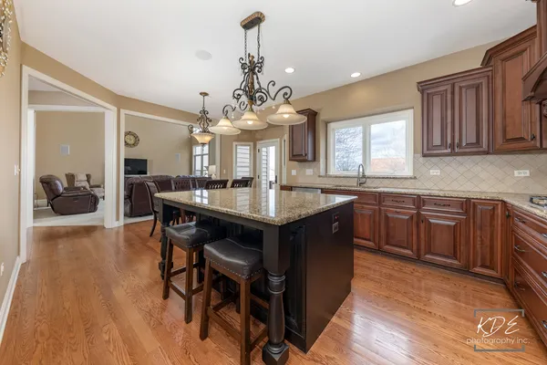 a kitchen with granite countertop a sink dishwasher a dining table and chairs with wooden floor