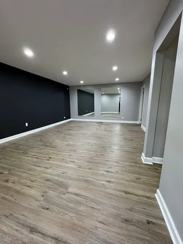 a view of an empty room with wooden floor and staircase