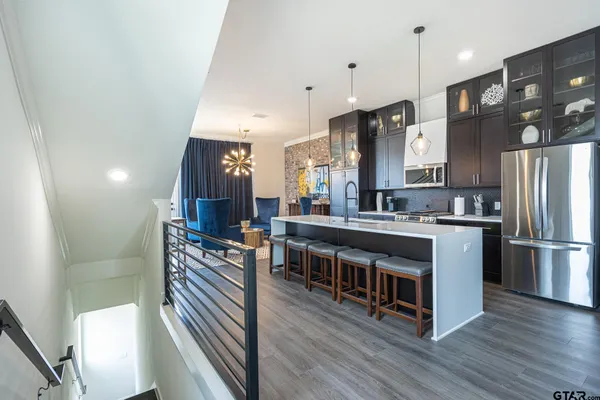 a kitchen with stainless steel appliances a refrigerator a stove a sink dishwasher and a dining table with wooden floor