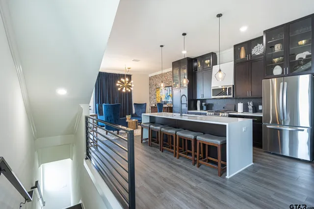 a kitchen with stainless steel appliances a refrigerator a stove a sink dishwasher and a dining table with wooden floor