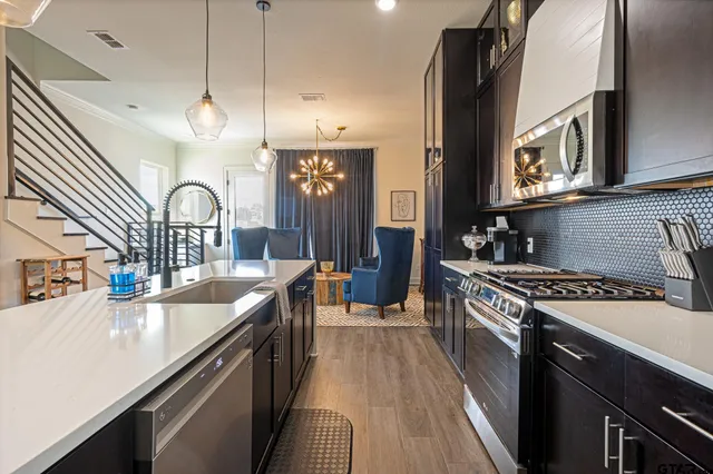 a kitchen with granite countertop a stove a sink a refrigerator and cabinets