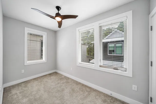 a view of empty room with windows and ceiling fan