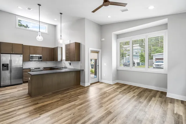 a large kitchen with stainless steel appliances granite countertop a stove a refrigerator a sink dishwasher with wooden floor and cabinets