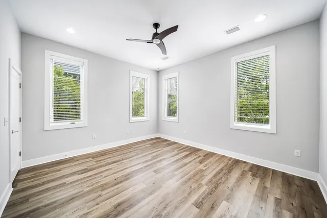 a view of empty room with wooden floor and fan