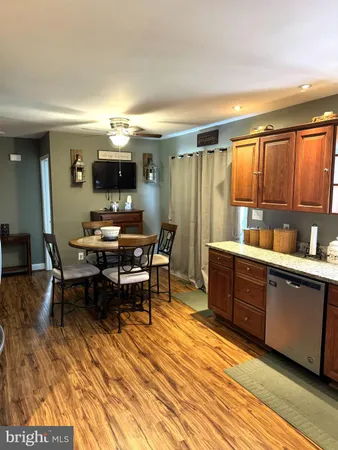 a dining hall with stainless steel appliances granite countertop a coffee table and chairs with wooden floor