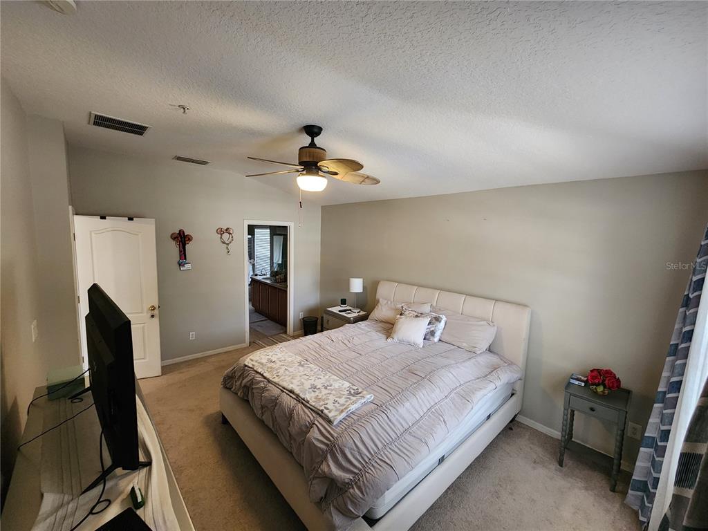 546 Climbing Ivy Court, Unit C Apopka, FL 32712 - Photo 13 of 26 a bedroom with a bed and a flat tv screen on the dresser