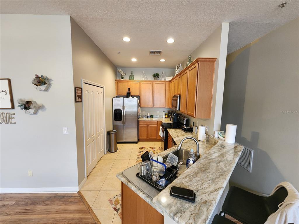 546 Climbing Ivy Court, Unit C Apopka, FL 32712 - Photo 6 of 26 a kitchen with stainless steel appliances granite countertop a refrigerator and a stove top oven