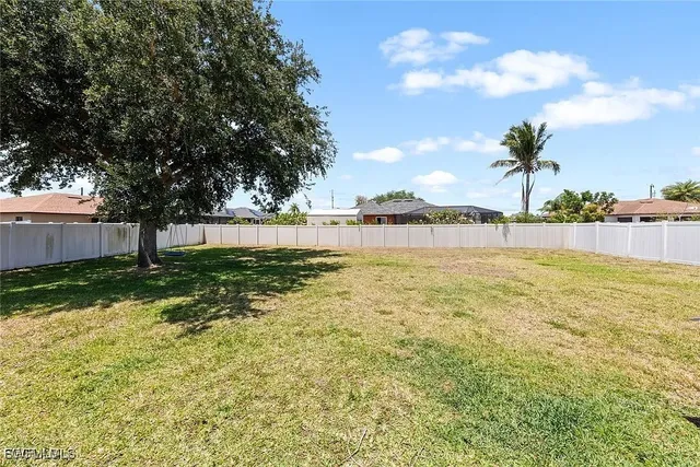 a view of yard with swimming pool and wooden fence