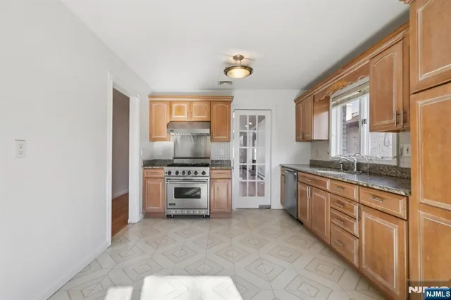 a kitchen with stainless steel appliances granite countertop a stove a sink and a refrigerator