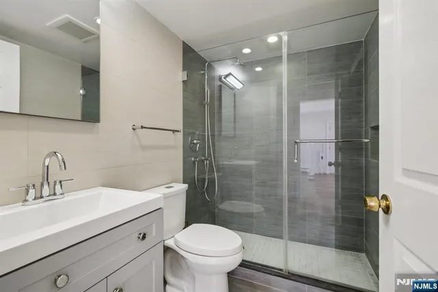 a bathroom with a shower sink vanity mirror and toilet