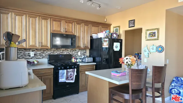 a kitchen with stainless steel appliances kitchen island granite countertop a refrigerator and a stove