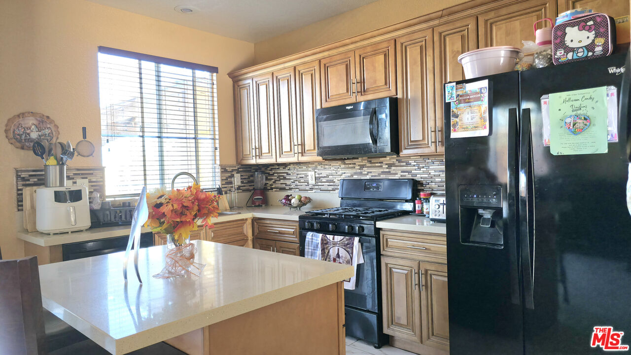 11532 Autumn Street Adelanto, CA 92301 - Photo 9 of 32 a kitchen with stainless steel appliances granite countertop a sink refrigerator and a stove