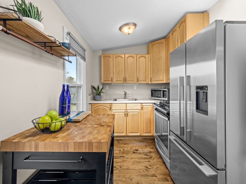47 R Jamaica Street, Unit 3 Boston, MA 02130 - Photo 6 of 18 a kitchen with kitchen island granite countertop a refrigerator a sink and white cabinets