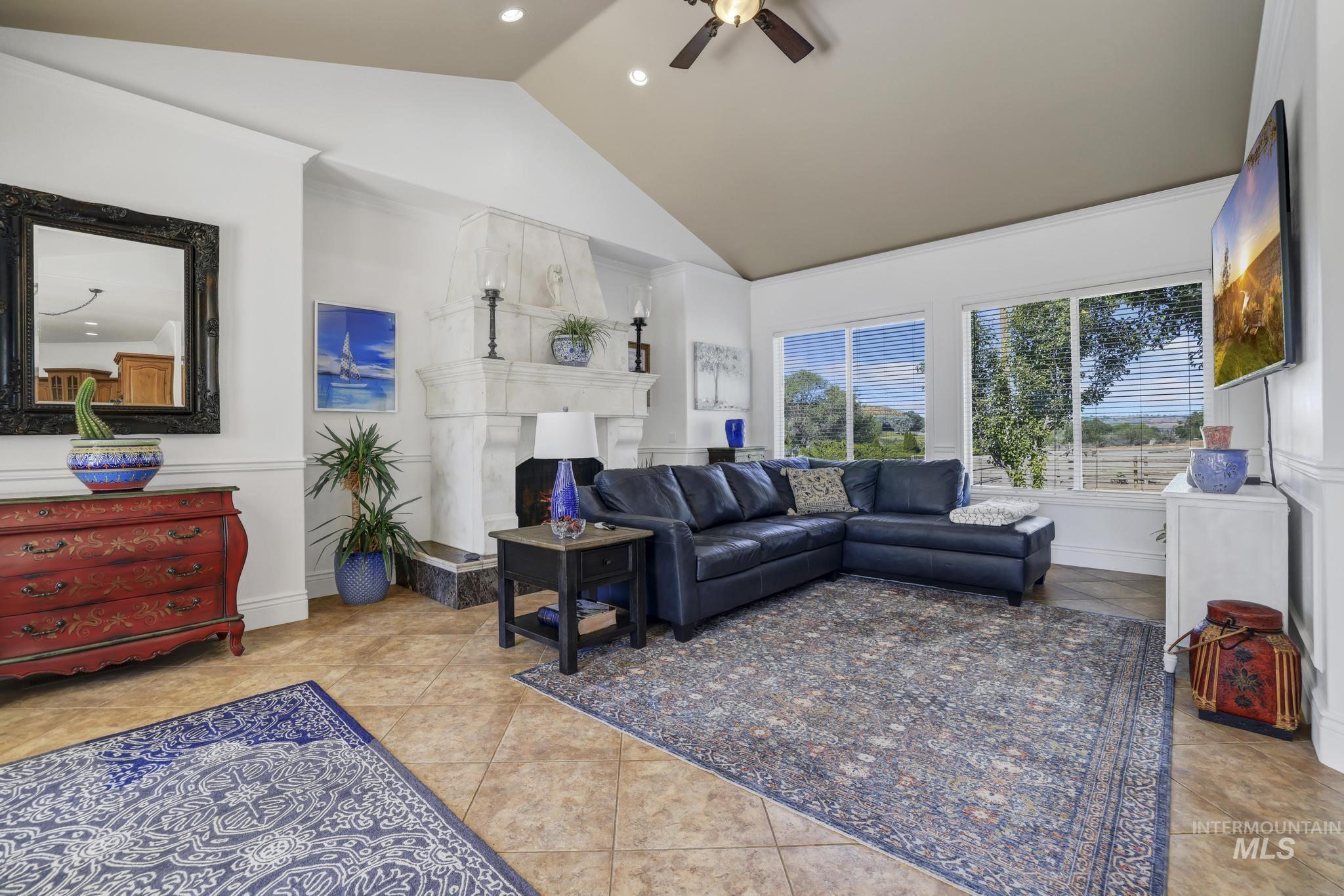 1301 Kanaka Rapids Road Buhl, ID 83316 - Photo 30 of 50 Spacious living area featuring a vaulted ceiling with a ceiling fan, a prominent fireplace with a carved mantel, tile flooring, and large windows providing abundant natural light
