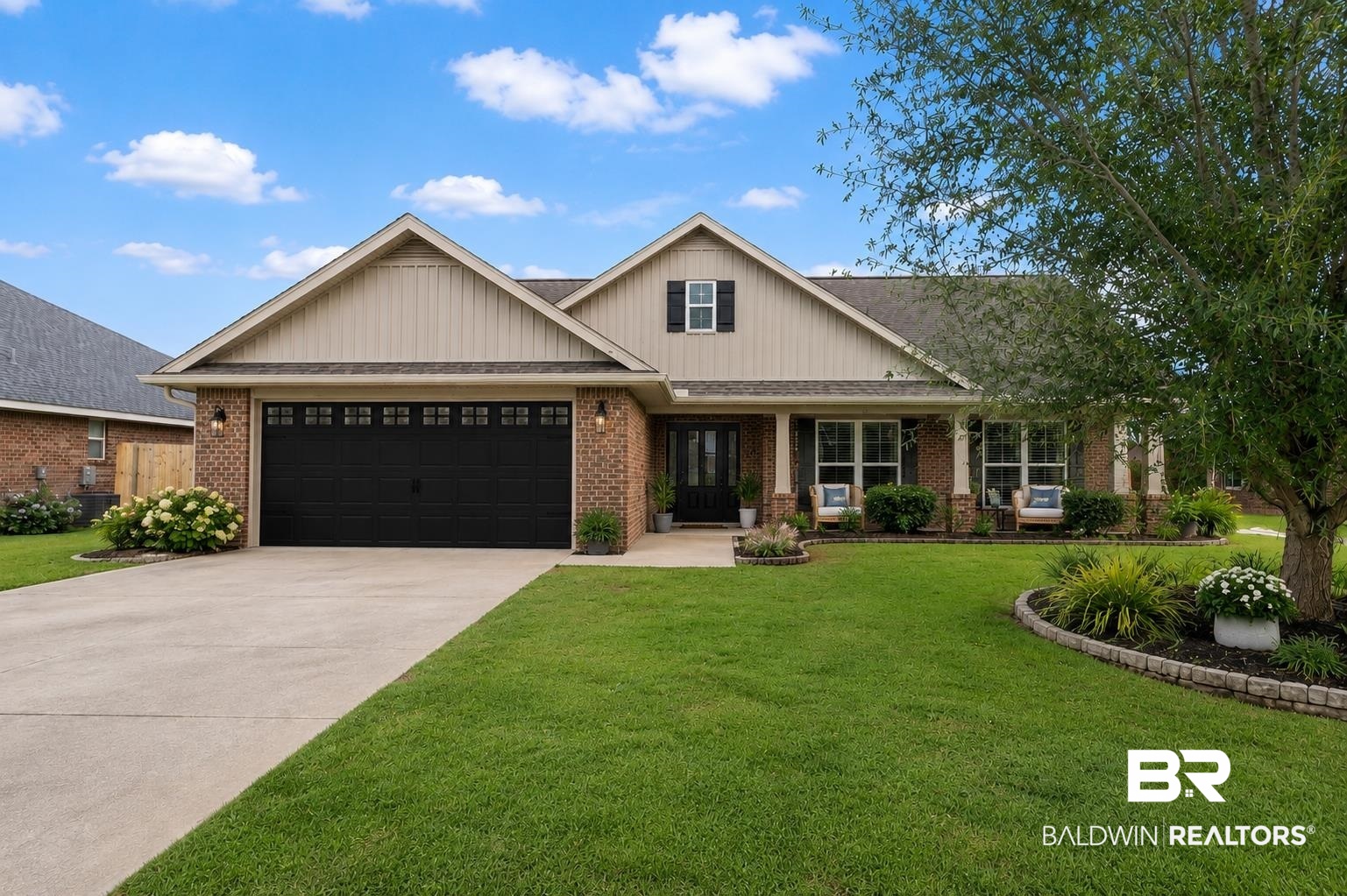 562 Vestige Mews Foley, AL 36535 - Photo 54 of 54 AI Edited Image: Brick facade home with a covered front porch, dark garage door, and a concrete driveway