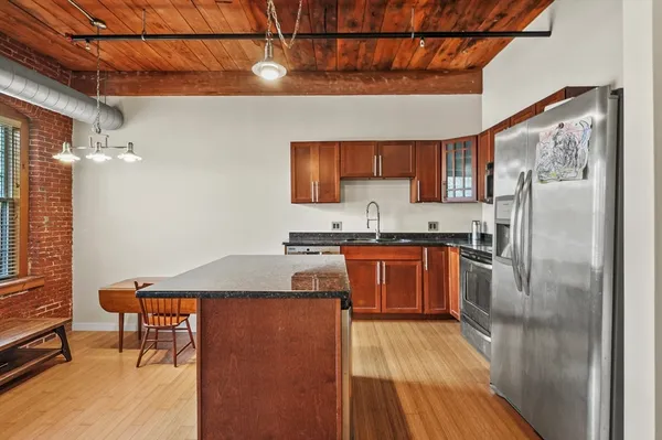 a kitchen with stainless steel appliances granite countertop a refrigerator a sink dishwasher a stove and white countertops with wooden floor