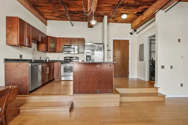 a kitchen with stainless steel appliances granite countertop a sink dishwasher and a stove with wooden floor
