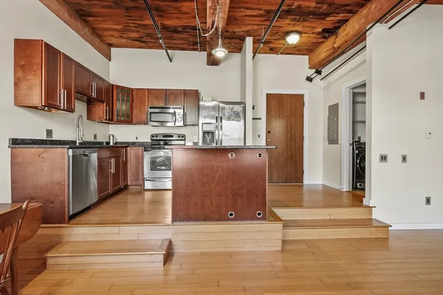 a kitchen with stainless steel appliances granite countertop a sink dishwasher and a stove with wooden floor
