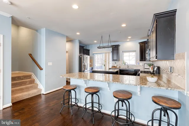 a kitchen with stainless steel appliances granite countertop wooden floor and refrigerator