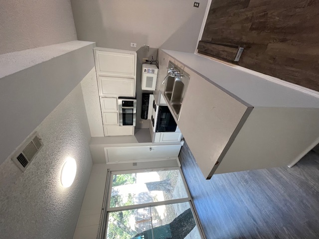 12613 Tree Line Drive, Unit A Austin, TX 78729 - Photo 4 of 15 a kitchen with kitchen island a stove a sink a microwave and wooden floor