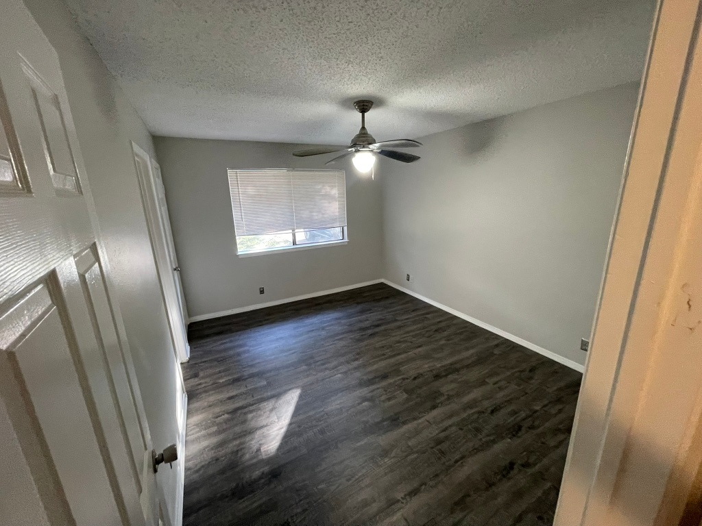 12613 Tree Line Drive, Unit A Austin, TX 78729 - Photo 8 of 15 an empty room with wooden floor fan and window