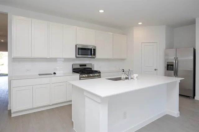 a kitchen with stainless steel appliances a sink a stove a microwave a sink a refrigerator and cabinets