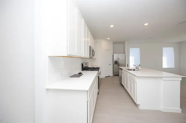 a kitchen with a sink a stove top oven and white cabinets