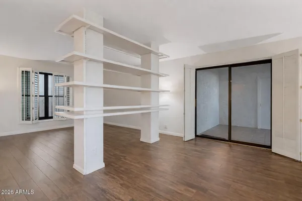 a view of an empty room with wooden floor and a window
