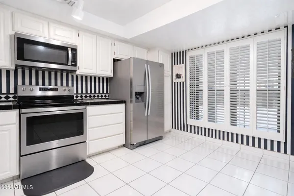 a kitchen with granite countertop a stove a microwave and a refrigerator